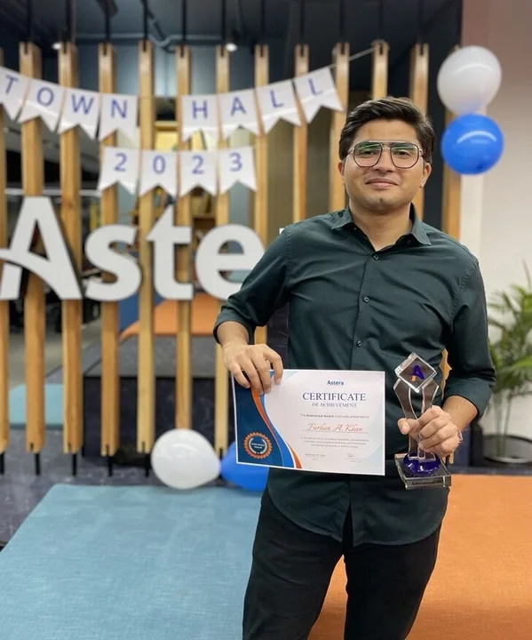 Holding the Employee of the Year certificate and trophy at a company town hall