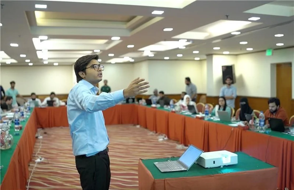 Teaching a bootcamp to a room arranged in a horseshoe, arm out mid-explanation