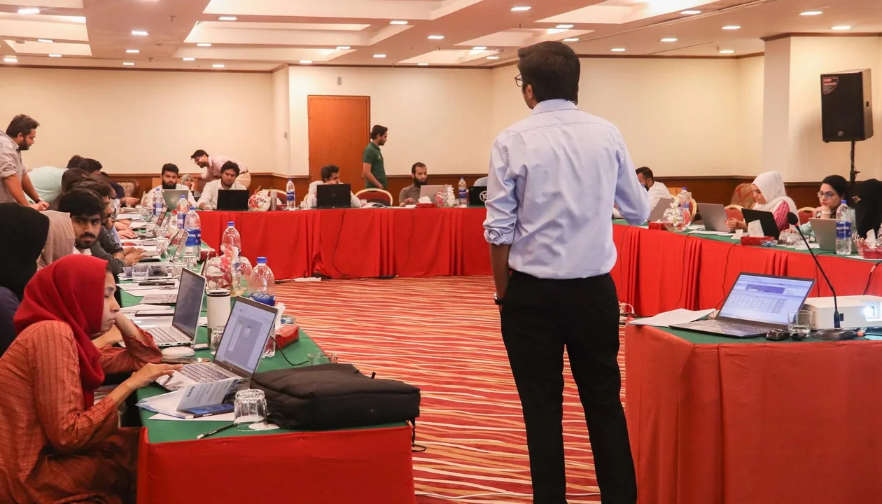 A long training room seen from the back, every seat taken and every laptop open